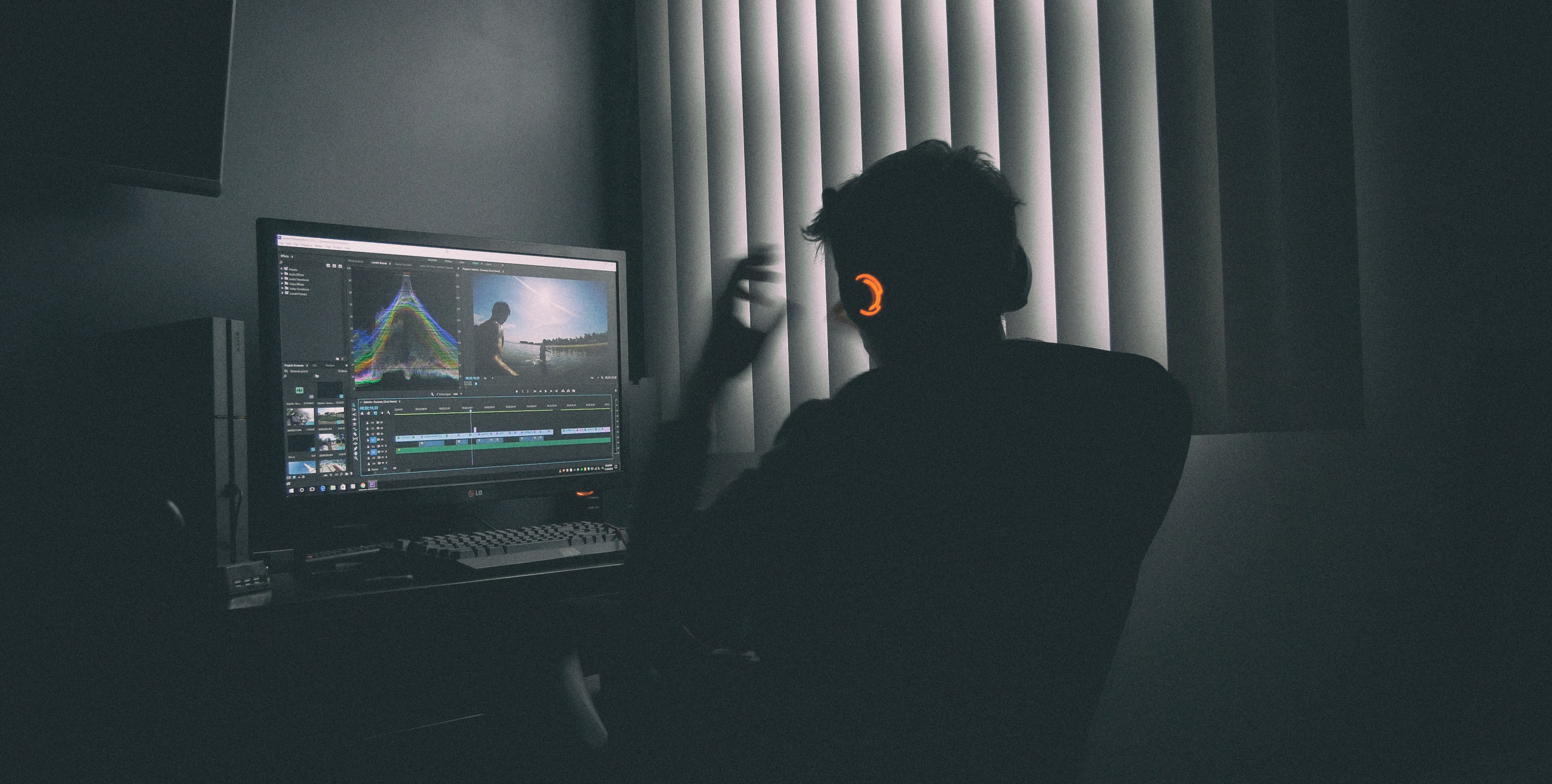 A man in front of a computer screen in the dark