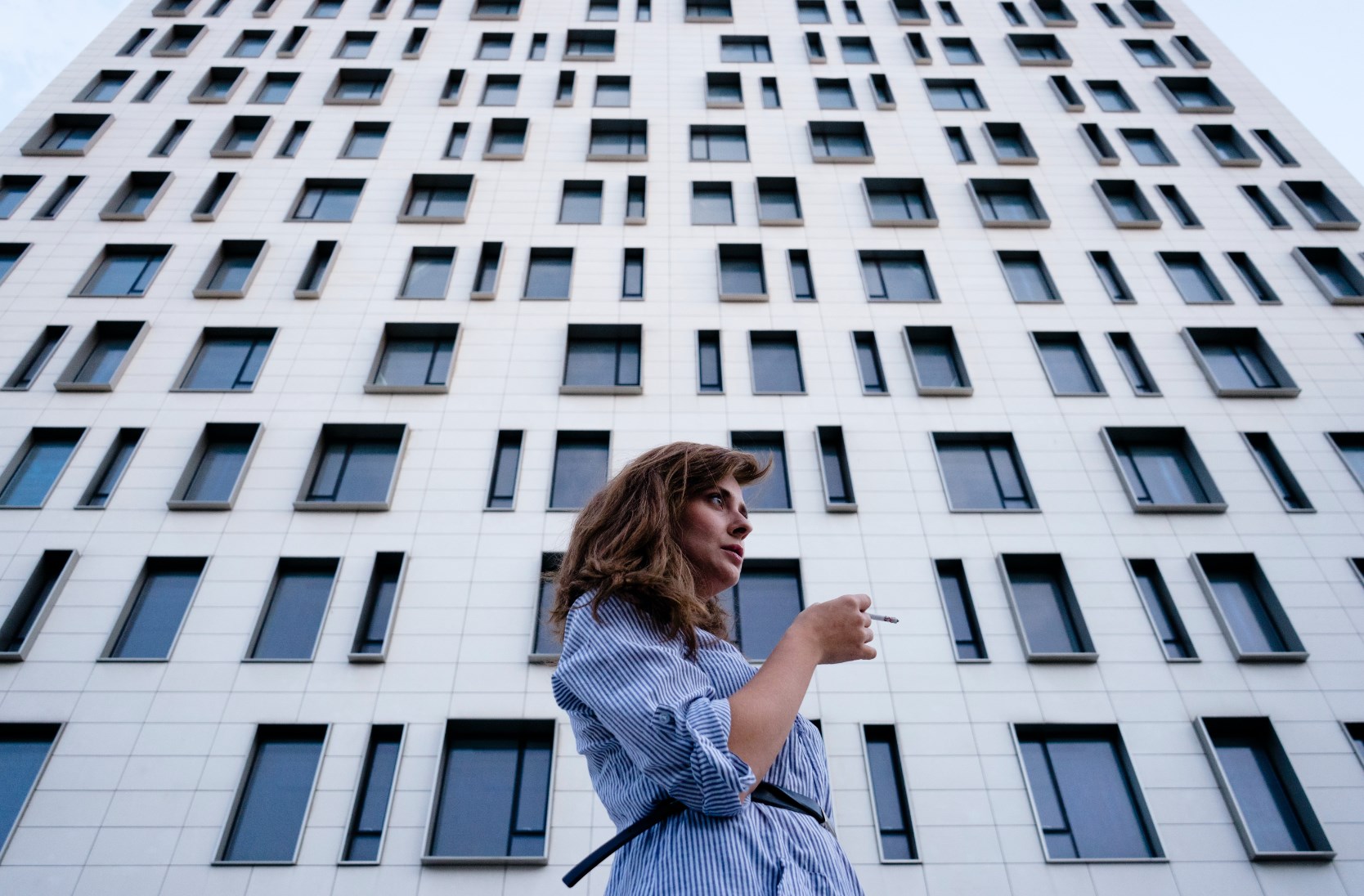 Woman Smoking a Cigarette in front of a Building Perspective